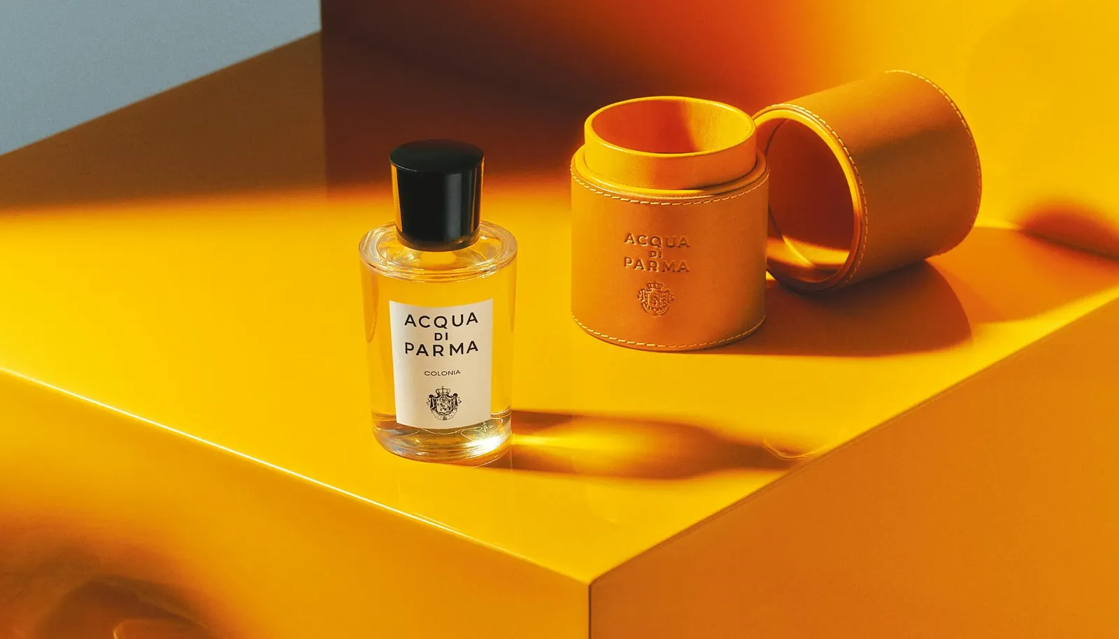 Flacon Acqua di Parma Colonia et étui en cuir sur un décor jaune lumineux