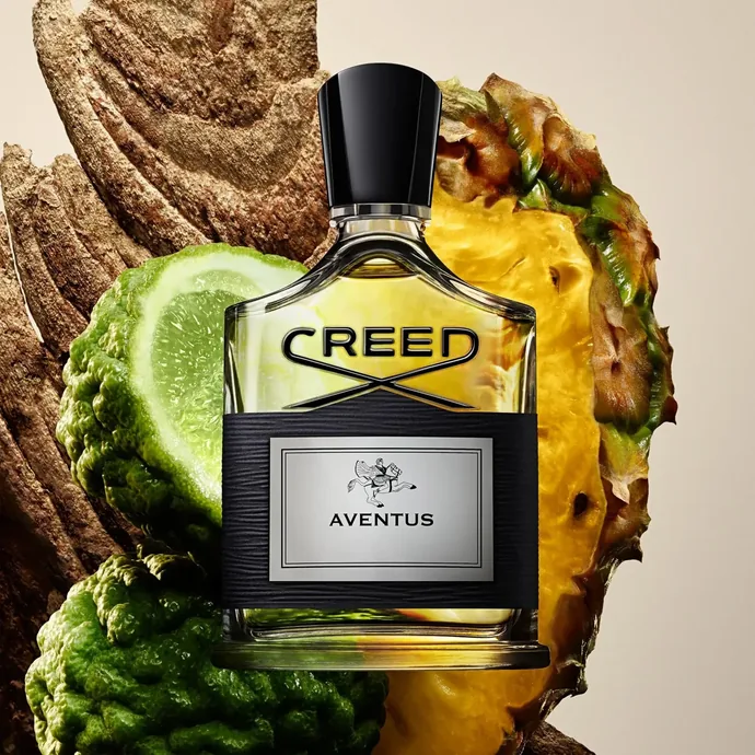 Flacon Creed Aventus accompagné d'éléments évoquant son accord fruité et boisé