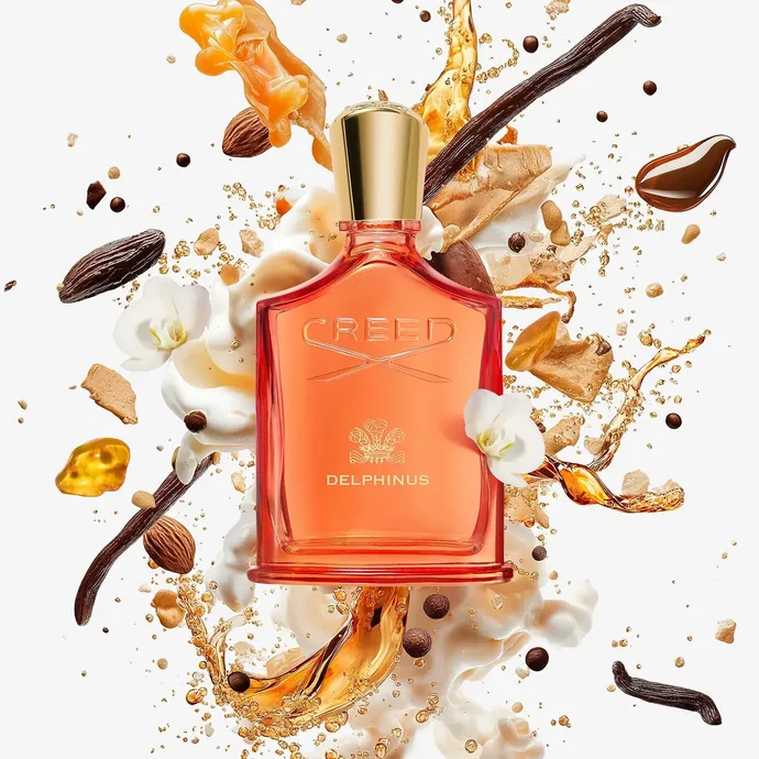 Flacon orange Creed Delphinus accompagné de matières évoquant l'encens, l'amande et la vanille