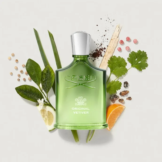 Flacon vert Creed Original Vetiver entouré de feuilles et d'agrumes