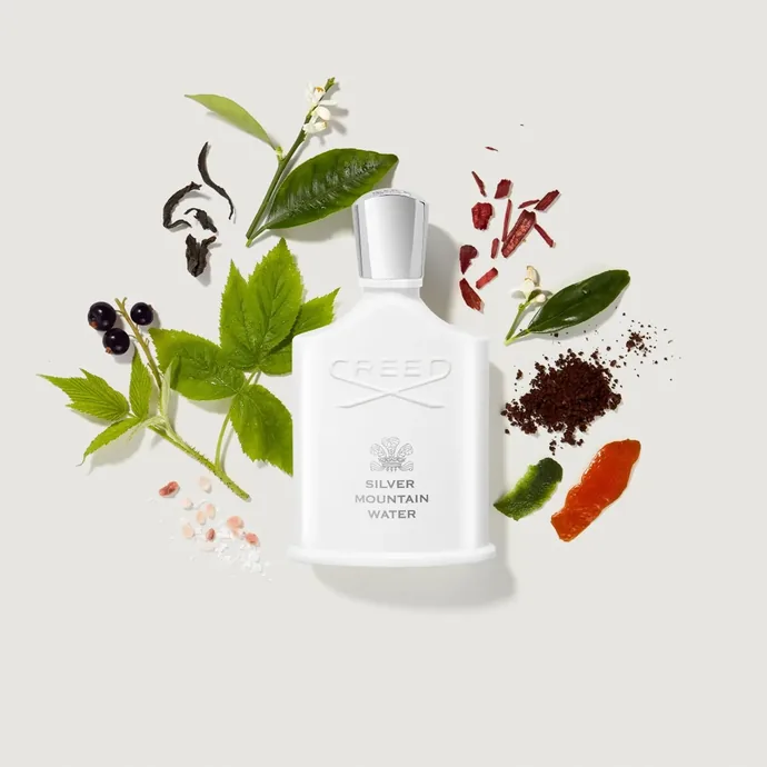 Flacon Creed Silver Mountain Water entouré de feuilles, d'épices et de fleurs