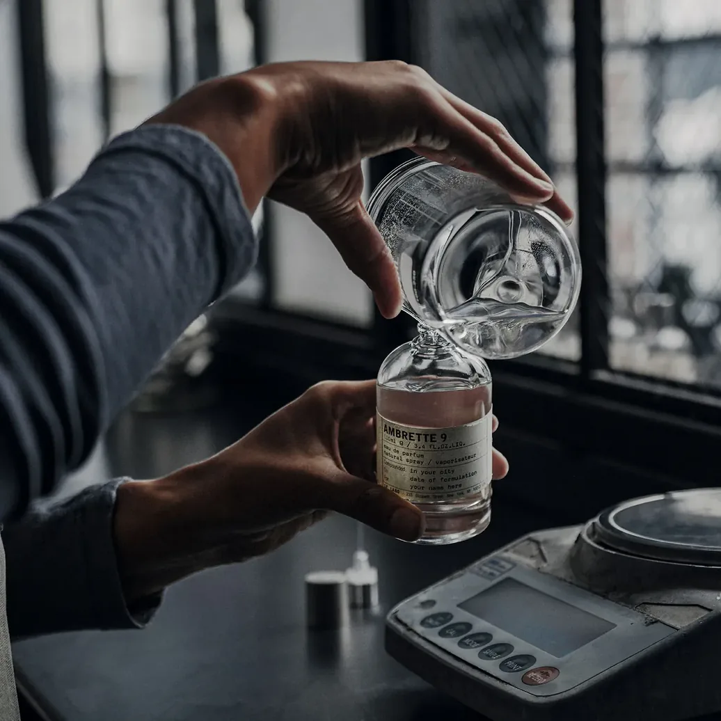 Préparation manuelle d'un flacon Ambrette 9 dans un laboratoire Le Labo